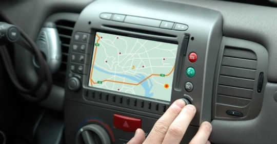 person pushing a button next to a gps screen in a car