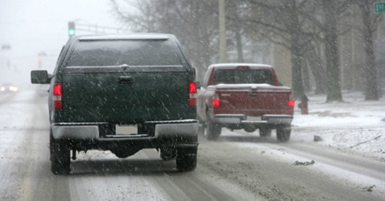 two trucks driving on a snow-covered road