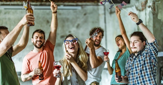 group of people wearing fourth of july glasses and shirts holding wine glasses and beer bottles