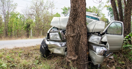 sports utility vehicle crashed into a tree on the side of a rural road